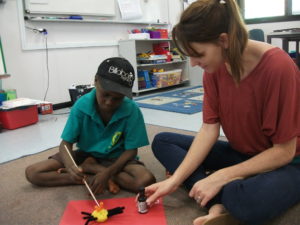 Inspiring teacher-linguist, Emma Browne, having fun making honey ants with a young learner in his community 'out bush'.