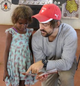 Joe Relic from HARs gives an impromptu reading lesson to an enthusiastic little learner in the Gibson desert.